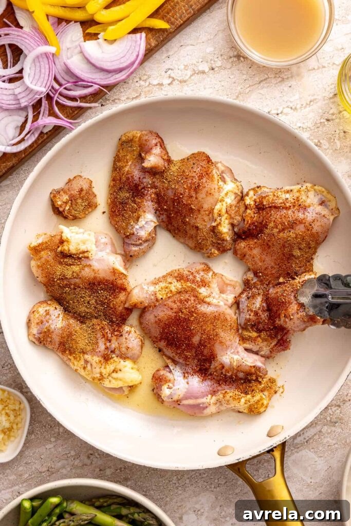 Wholesome Chicken Thigh Rice Bowls 5 Boneless, skinless chicken thighs searing in a cast-iron skillet with aromatic spices