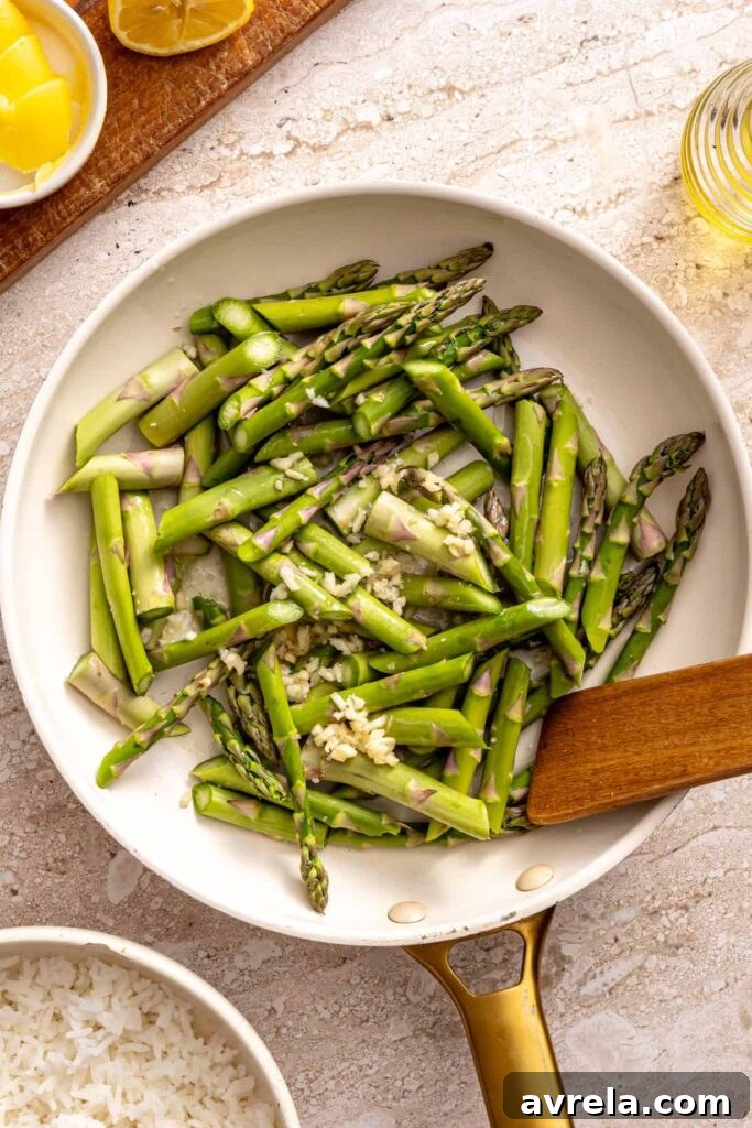 Wholesome Chicken Thigh Rice Bowls 6 Fresh asparagus spears being sautéed with minced garlic in a hot pan