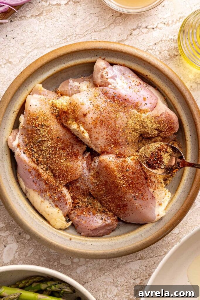 Wholesome Chicken Thigh Rice Bowls 8 Raw chicken thighs on a plate being generously seasoned with a spice blend
