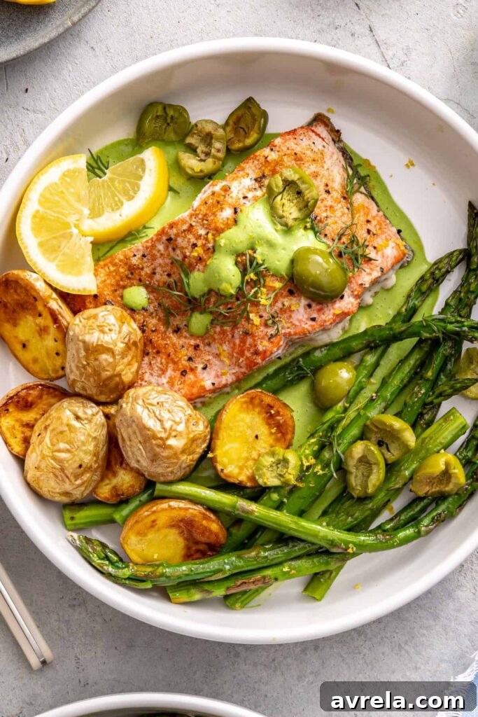 Baked salmon served with asparagus, herb sauce, potatoes, and olives