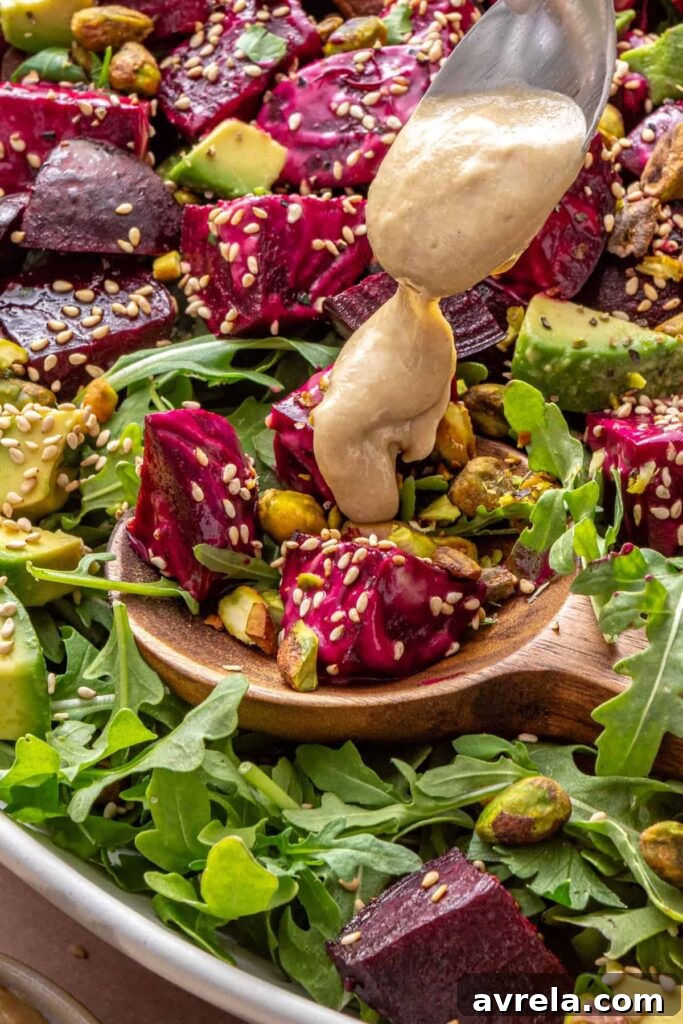 close-up of Tahini dressing being drizzled over roasted beet salad