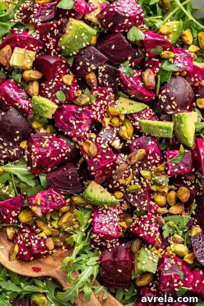 close-up texture shot of beet salad with goat cheese, avocados, sesame seeds and tahini dressing