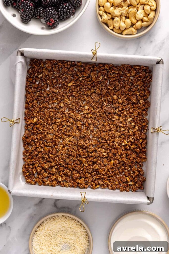 granola crust pressed into parchment-lined pan for blackberry cobbler bars