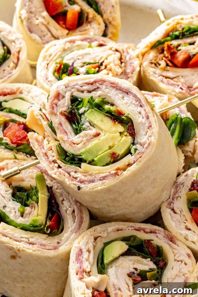 Stacked turkey pinwheels showing layers of turkey, cheese, avocado, and greens