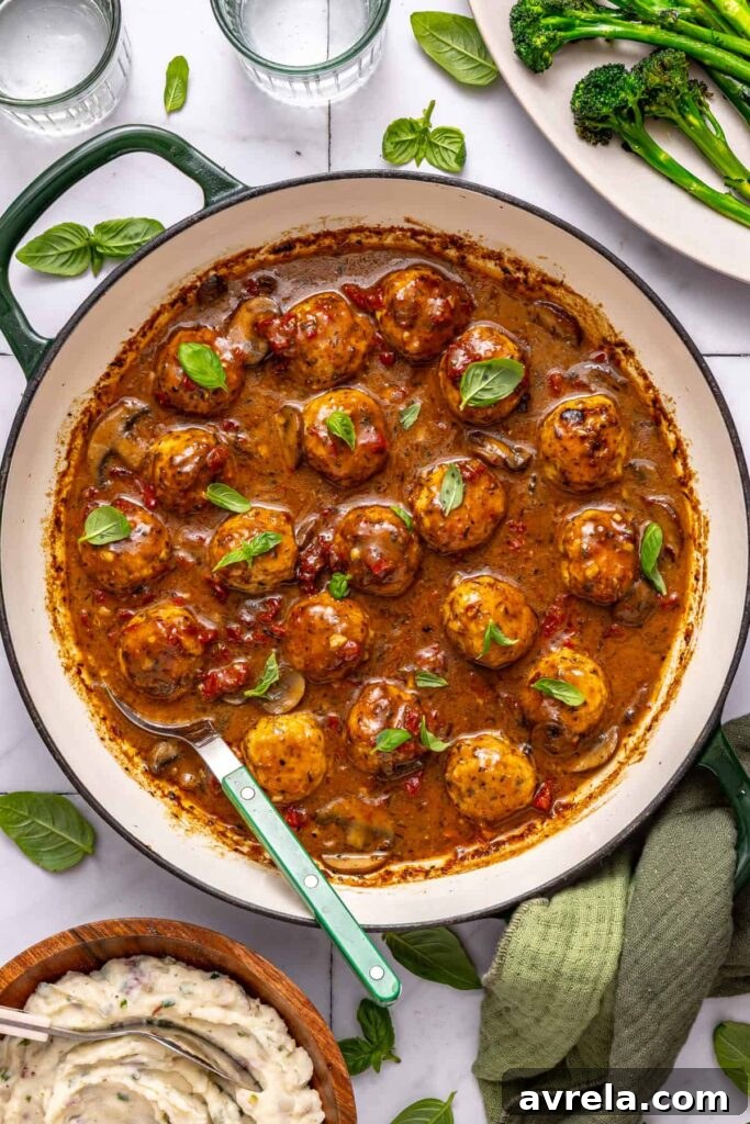 Creamy sun-dried tomato chicken meatballs with basil garnish on a set table