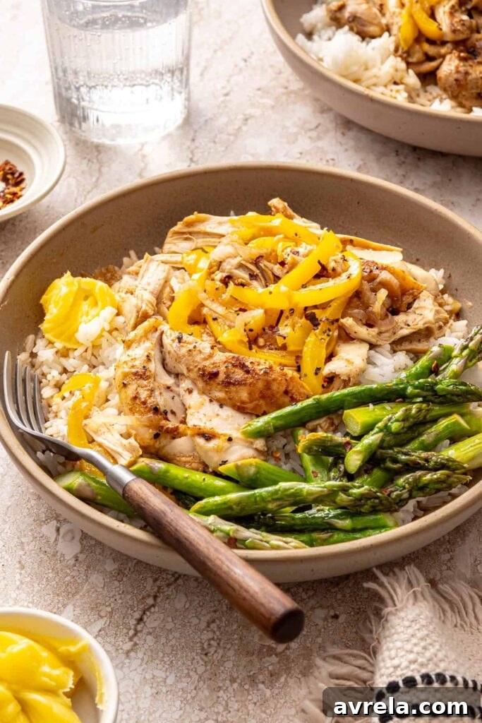 Side view of chicken thigh rice bowl with asparagus and peppers