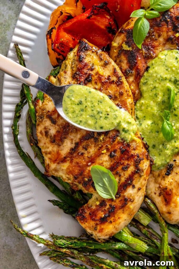 Spoon drizzling homemade pesto over grilled lemon pesto chicken