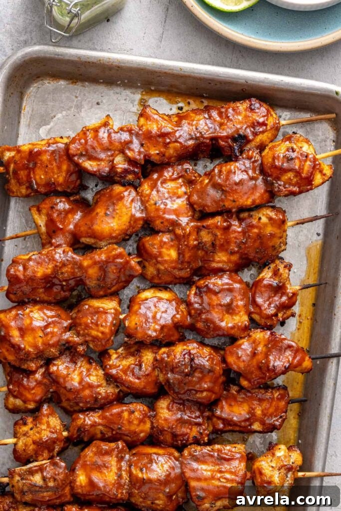 Overhead view of a sheet pan filled with grilled BBQ chicken skewers