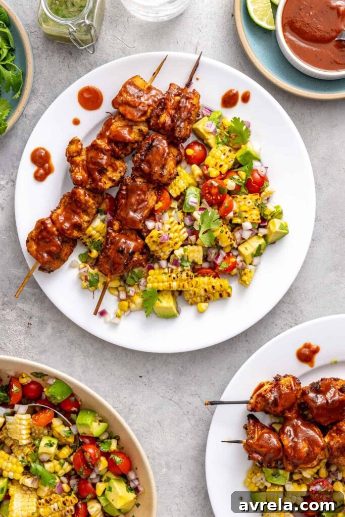 BBQ chicken skewers plated with fresh summer salad and BBQ sauce