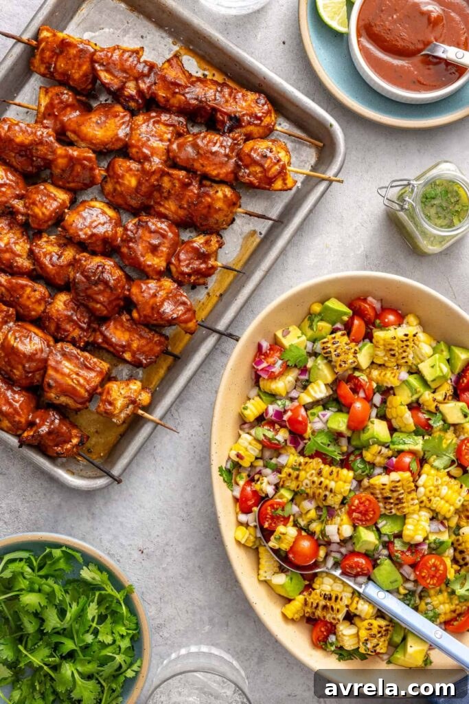 BBQ chicken skewers served with corn and tomato summer salad on a styled table