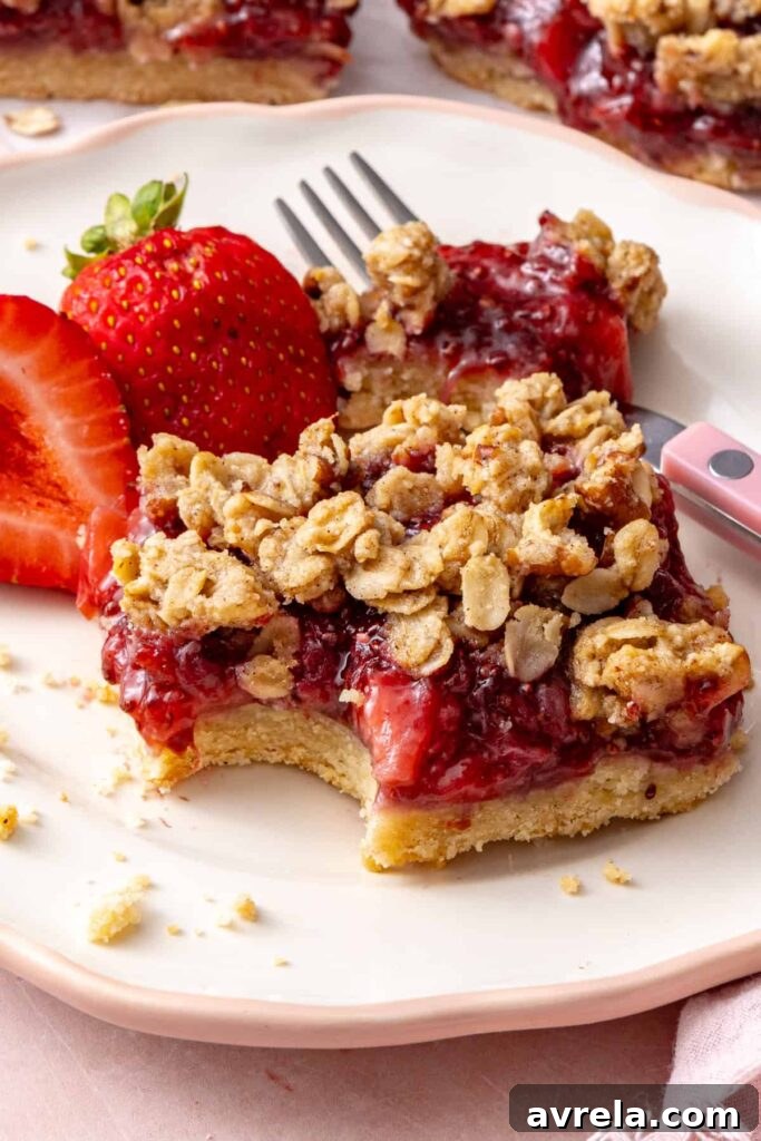 Strawberry oatmeal bar with a bite taken out, showing the soft strawberry filling and oat crumble.