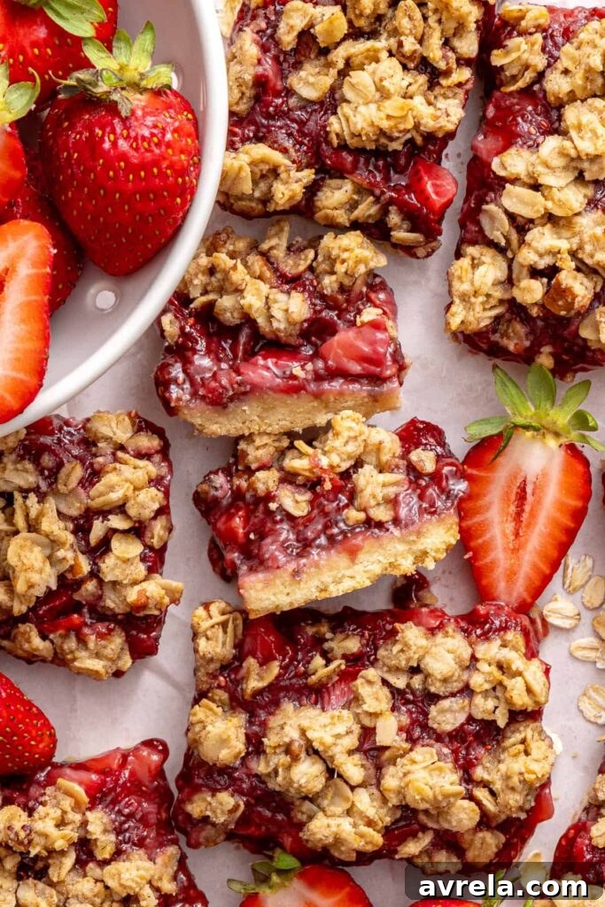Gluten-free strawberry oatmeal bars displayed on a styled table with fresh strawberries.