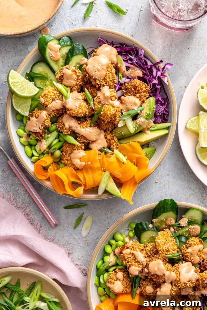 Overhead view of healthy air fryer bang bang shrimp bowls topped with creamy homemade bang bang sauce.