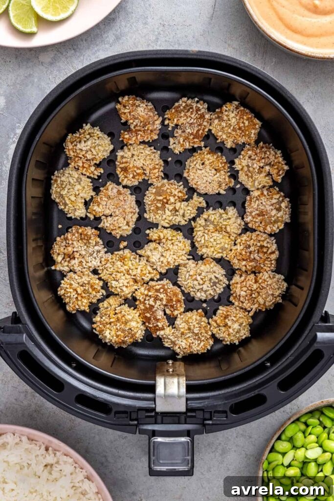 Breaded shrimp arranged in a single layer inside the air fryer basket before cooking
