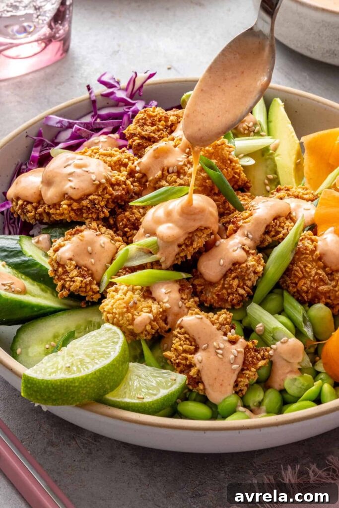 Creamy homemade bang bang sauce being drizzled over crispy air fryer shrimp bowls.