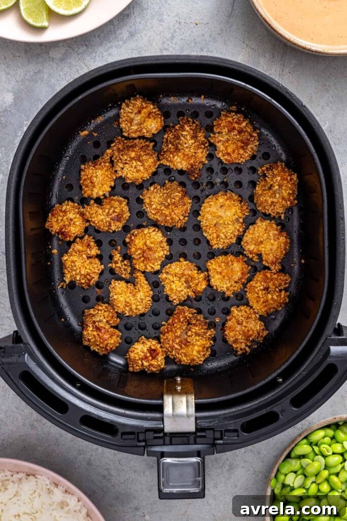 freshly cooked golden crispy shrimp resting in an air fryer basket