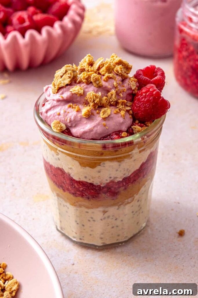 Peanut butter and jelly overnight oats topped with raspberry yogurt, peanut butter crumble, and a fresh raspberry