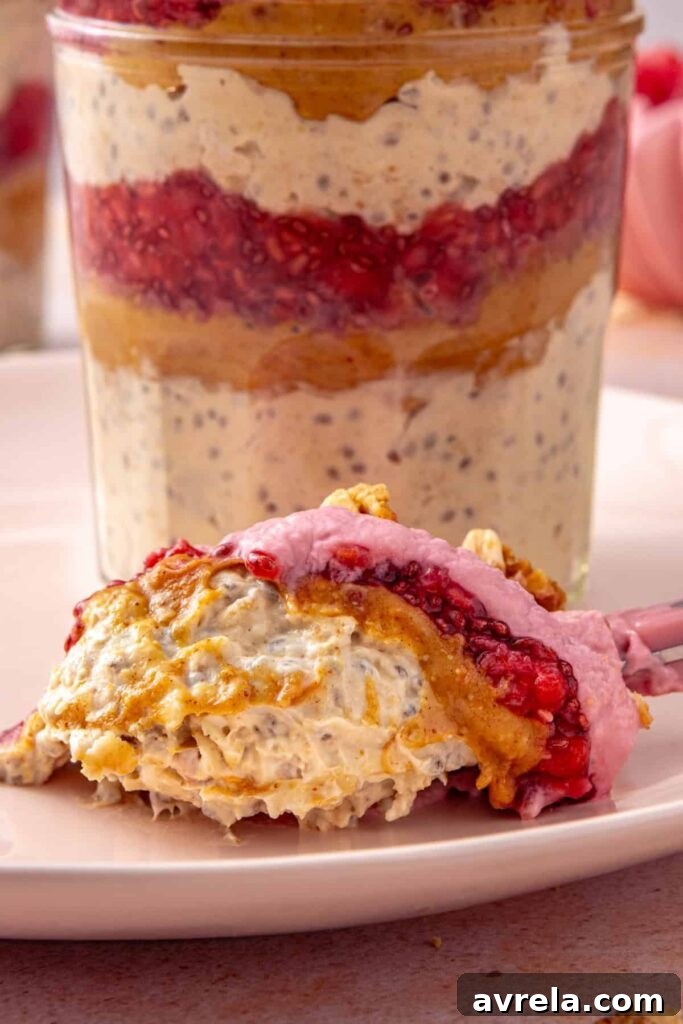 Spoonful of peanut butter and jelly overnight oats beside the serving jar