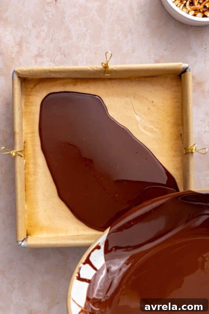 Pouring melted dark chocolate over the frozen peanut butter filling.