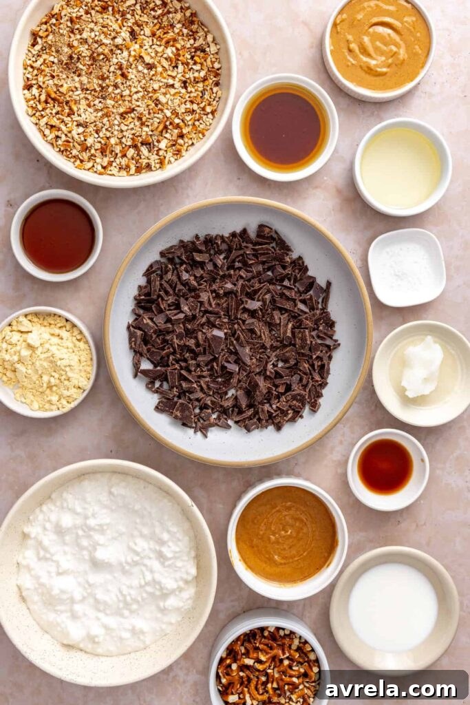 Overhead ingredients for frozen peanut butter pretzel bars including cottage cheese, peanut butter, gluten-free pretzels, dark chocolate, protein powder, maple syrup, and coconut oil.