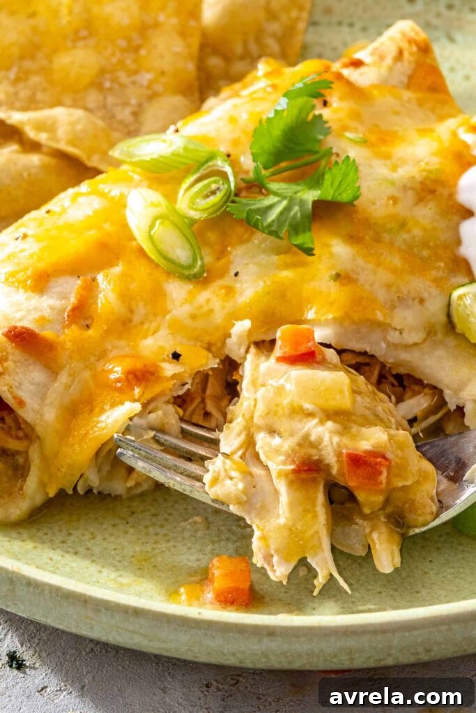 Baked Creamy Chicken Enchiladas with Salsa Verde 15 Fork lifting a bite of creamy green chicken enchiladas showing the cheesy shredded chicken filling