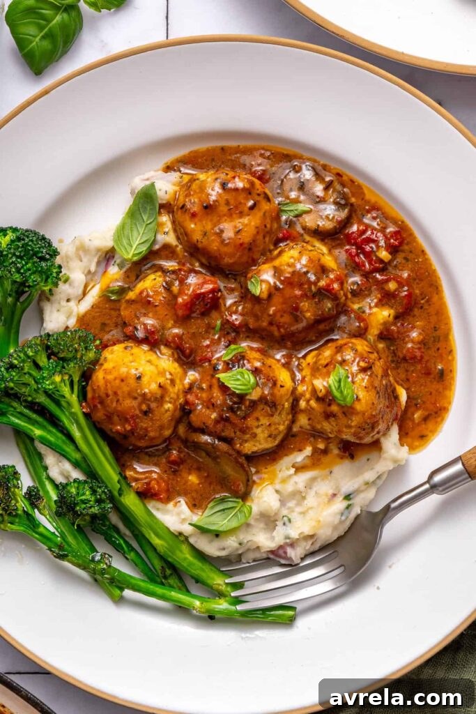 Plated marry me chicken meatballs dinner with mashed potatoes and greens