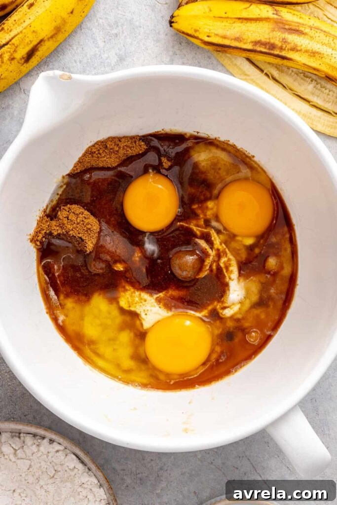 mashed bananas, eggs, vanilla extract, and Greek yogurt in a mixing bowl for banana birthday cake
