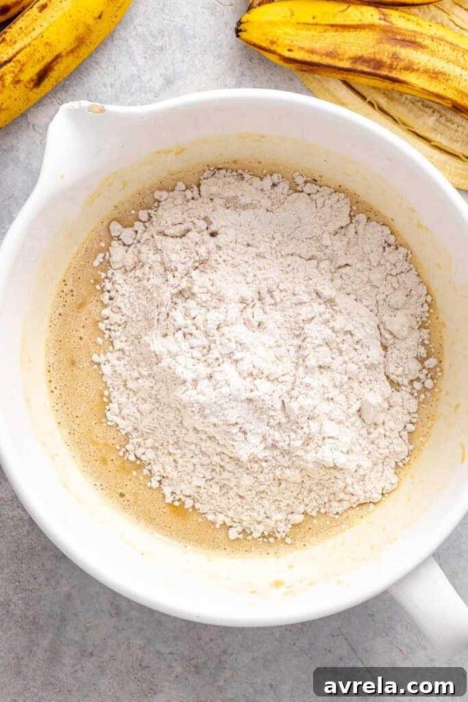 adding dry ingredients to wet ingredients for gluten-free vanilla banana birthday cake