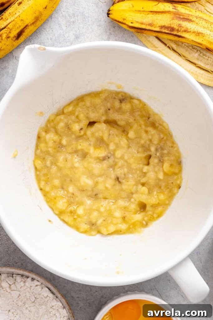 mashed bananas in a bowl, ready to be mixed with ingredients for a vanilla banana birthday cake for kids