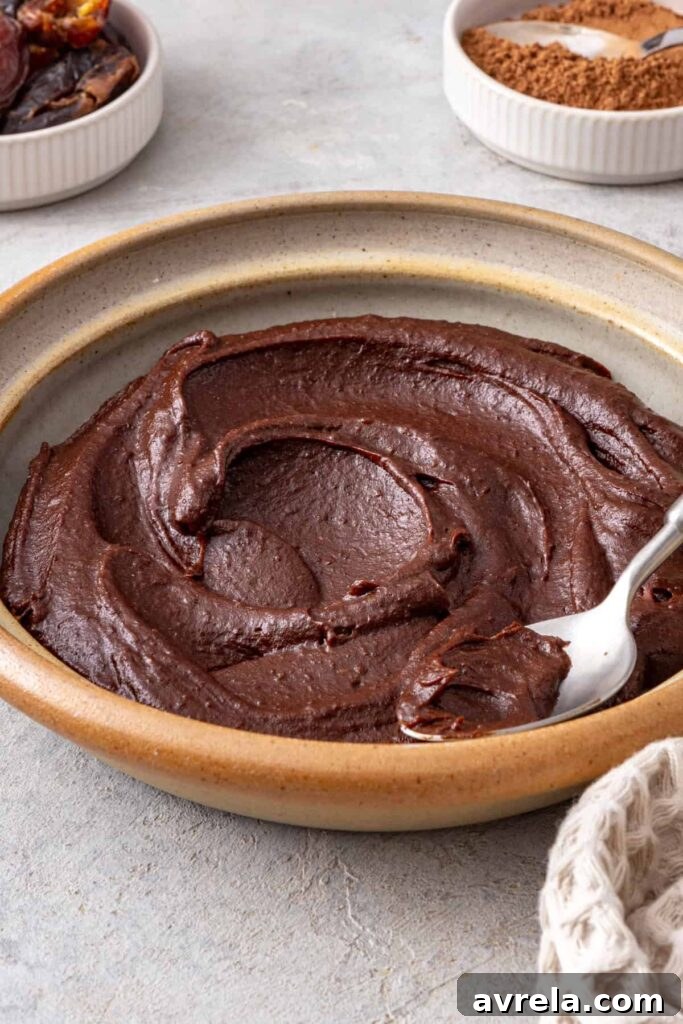 Thick healthy chocolate frosting lifted from the bowl with a spoon
