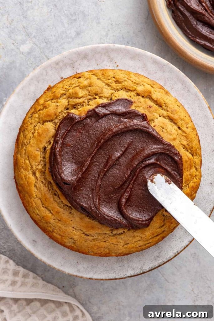 Spreading healthy chocolate date frosting over healthy banana birthday cake