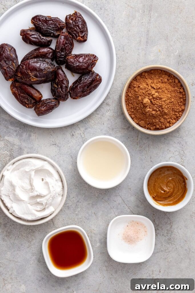 Ingredients for healthy chocolate frosting including Medjool dates, coconut cream, cacao powder, almond butter, and vanilla.