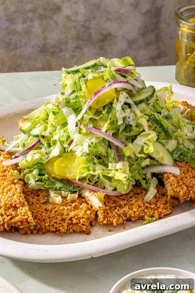 Close-up of crispy pickle chicken cutlet topped with creamy dill salad