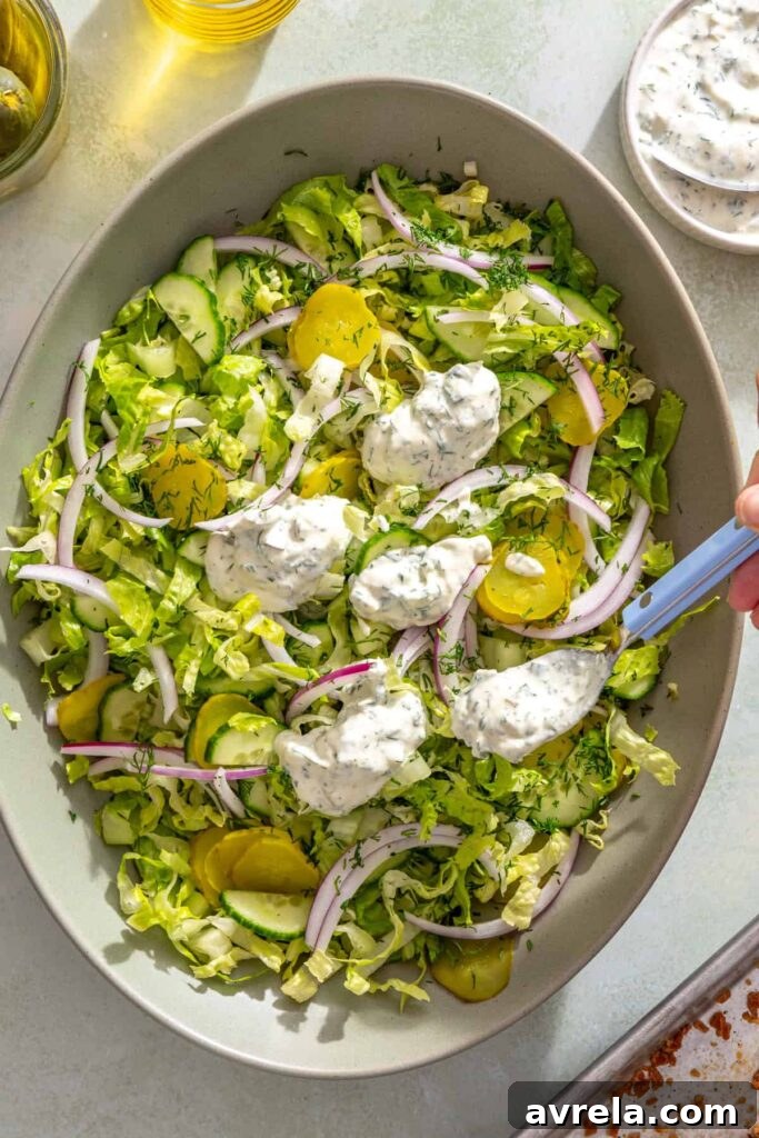 Adding creamy Greek yogurt pickle ranch to the shredded romaine salad