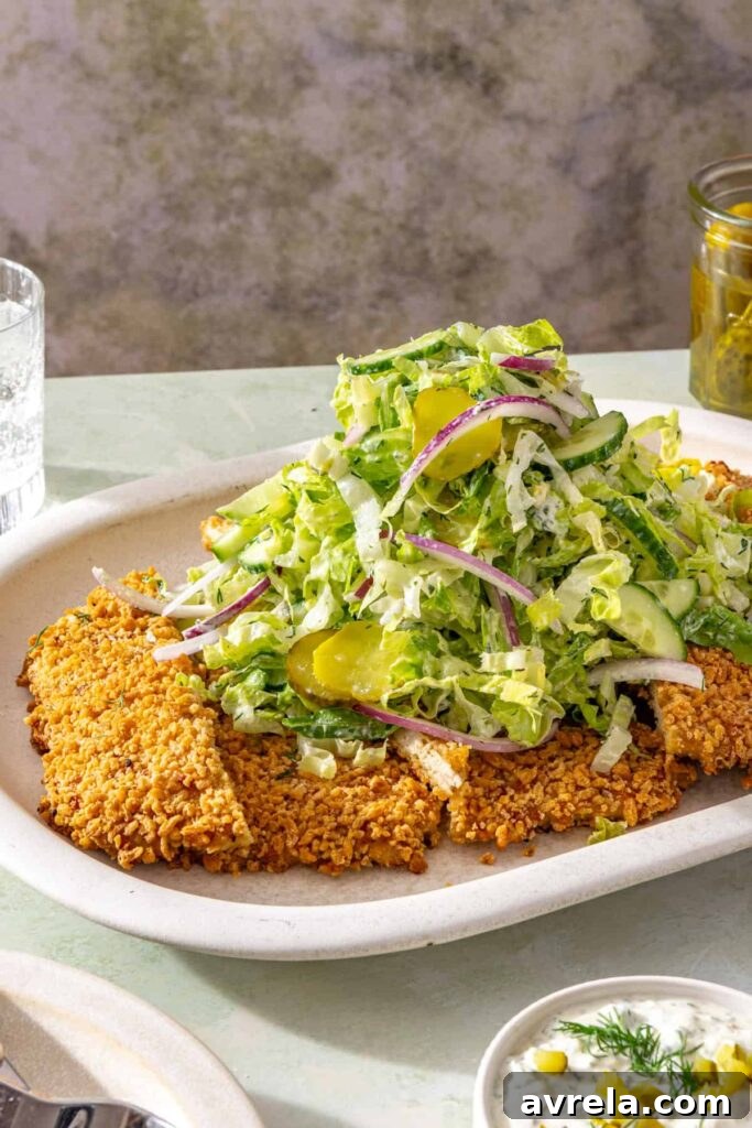 Crispy panko-crusted chicken cutlet topped with cucumber and dill pickle salad
