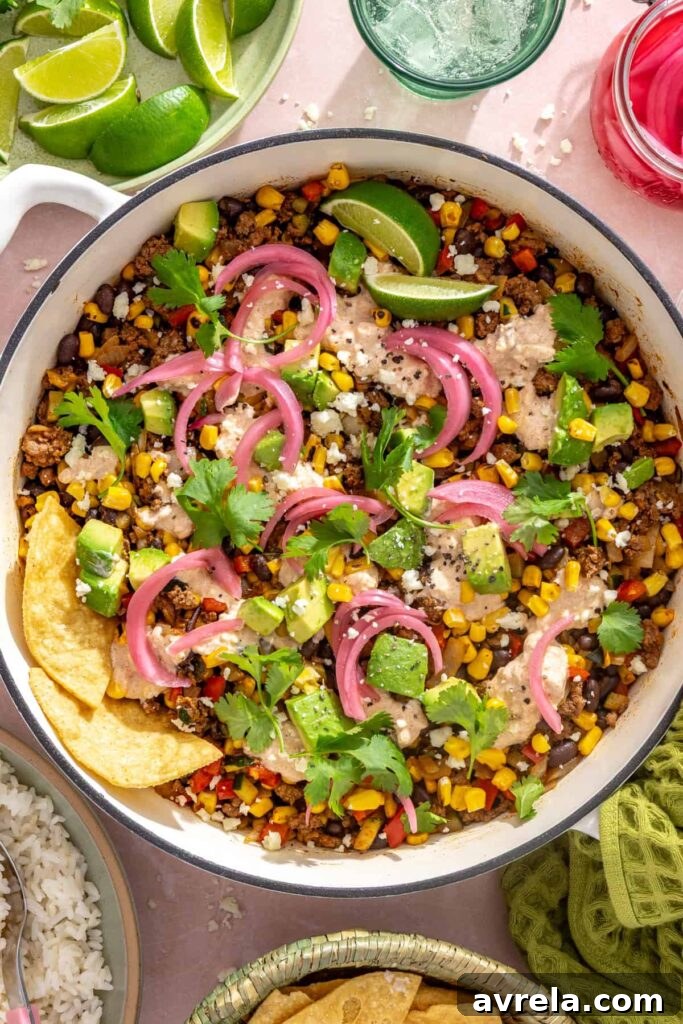 High-Protein Street Corn Taco Skillet One-Pan Dinner 2 Overhead view of finished street corn taco skillet garnished with cotija, cilantro, lime, and tortilla chips