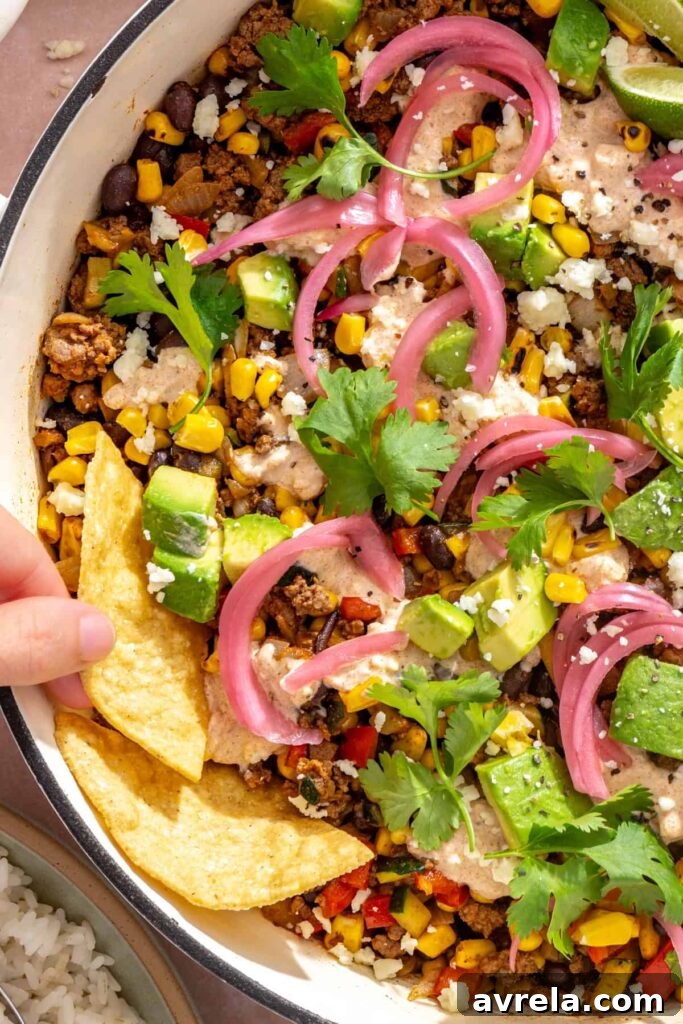 High-Protein Street Corn Taco Skillet One-Pan Dinner 4 Tortilla chips being dipped into creamy street corn taco skillet