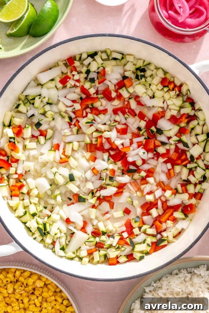 High-Protein Street Corn Taco Skillet One-Pan Dinner 8 Diced onion, bell pepper, and zucchini cooking in a skillet for street corn taco skillet