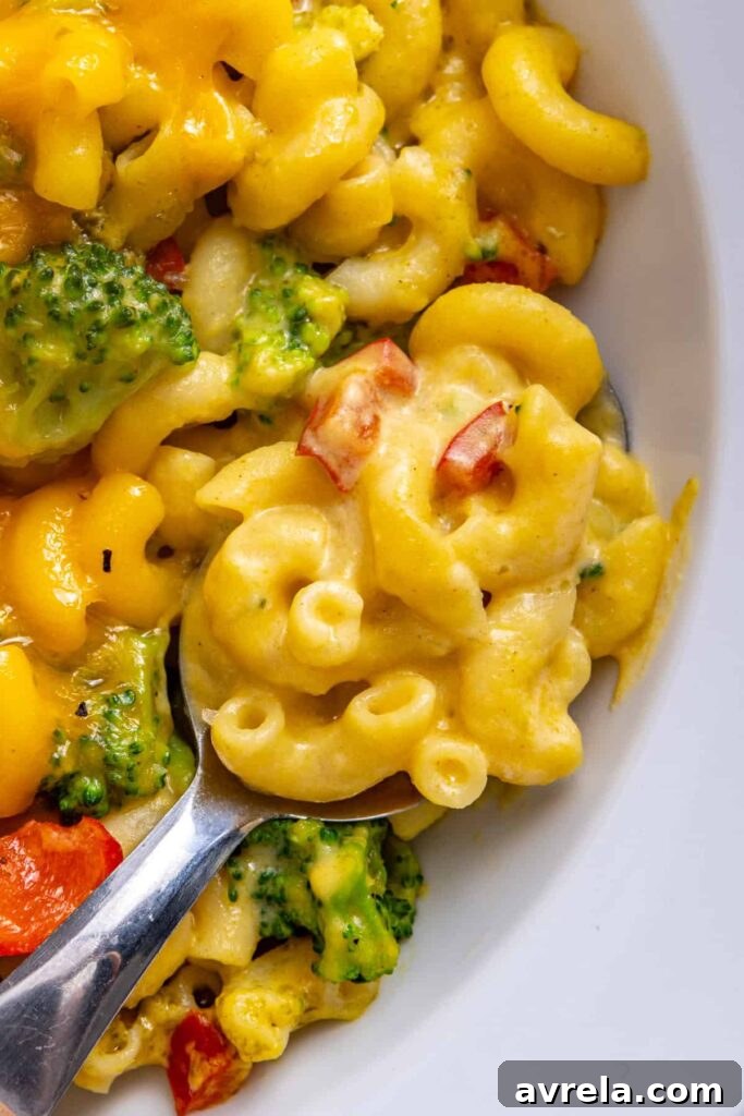 Close-up of a serving of broccoli cheddar pasta with a spoon ready to scoop