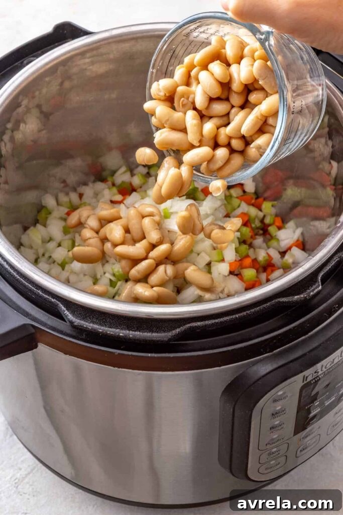 pouring beans into an Instant Pot with chicken thighs and vegetables for buffalo chicken chili