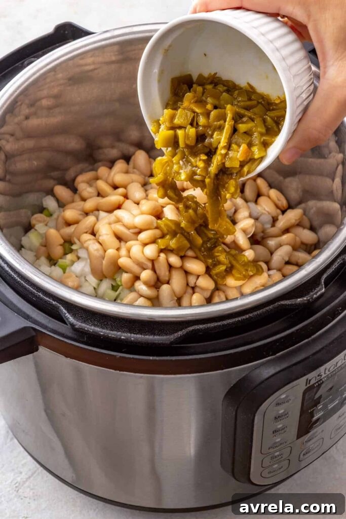 green chiles being poured into the Instant Pot as part of a buffalo chicken chili recipe