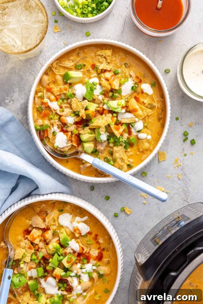 Overhead bowl of creamy buffalo chicken chili served with a spoon and extra buffalo sauce