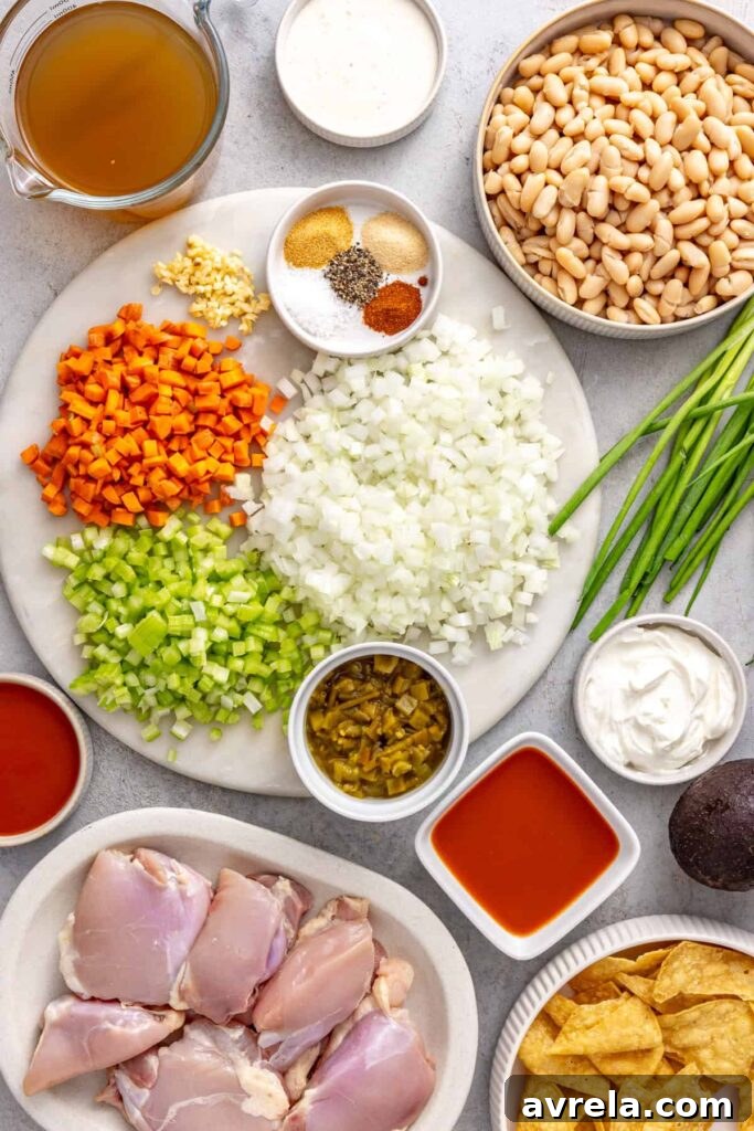 Ingredients for Instant Pot buffalo chicken chili including chicken thighs, cannellini beans, vegetables, green chiles and buffalo sauce