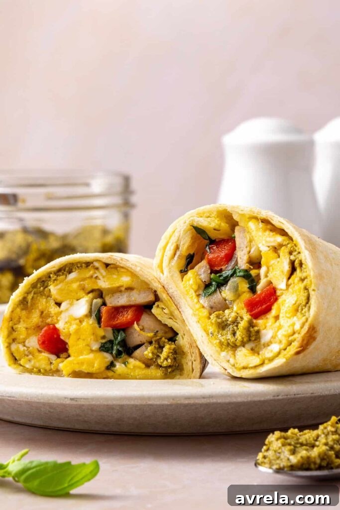 High-protein chicken breakfast burrito cut in half with eggs, chicken sausage, spinach, roasted red peppers and mozzarella