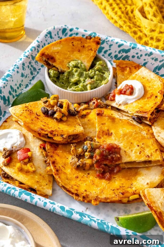 Crispy sheet pan quesadillas served on a tray with guacamole, lime and dipping sauces