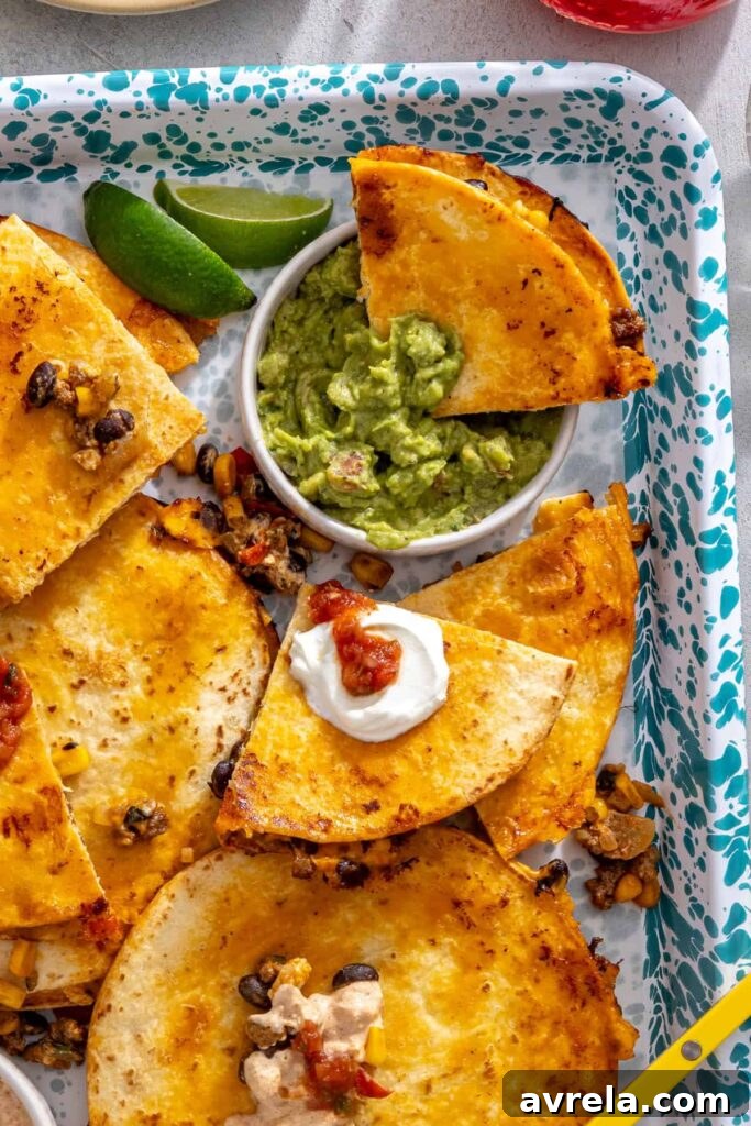 Sheet pan quesadilla wedge dipped into guacamole with crispy wedges on a serving tray