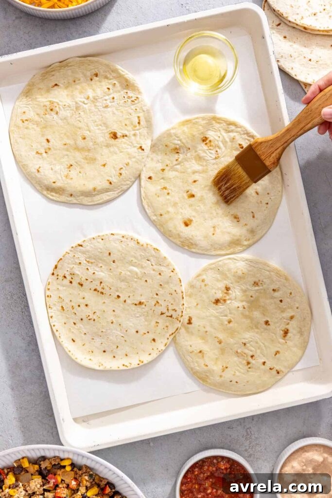 Tortillas brushed with avocado oil and flipped onto a parchment-lined sheet pan