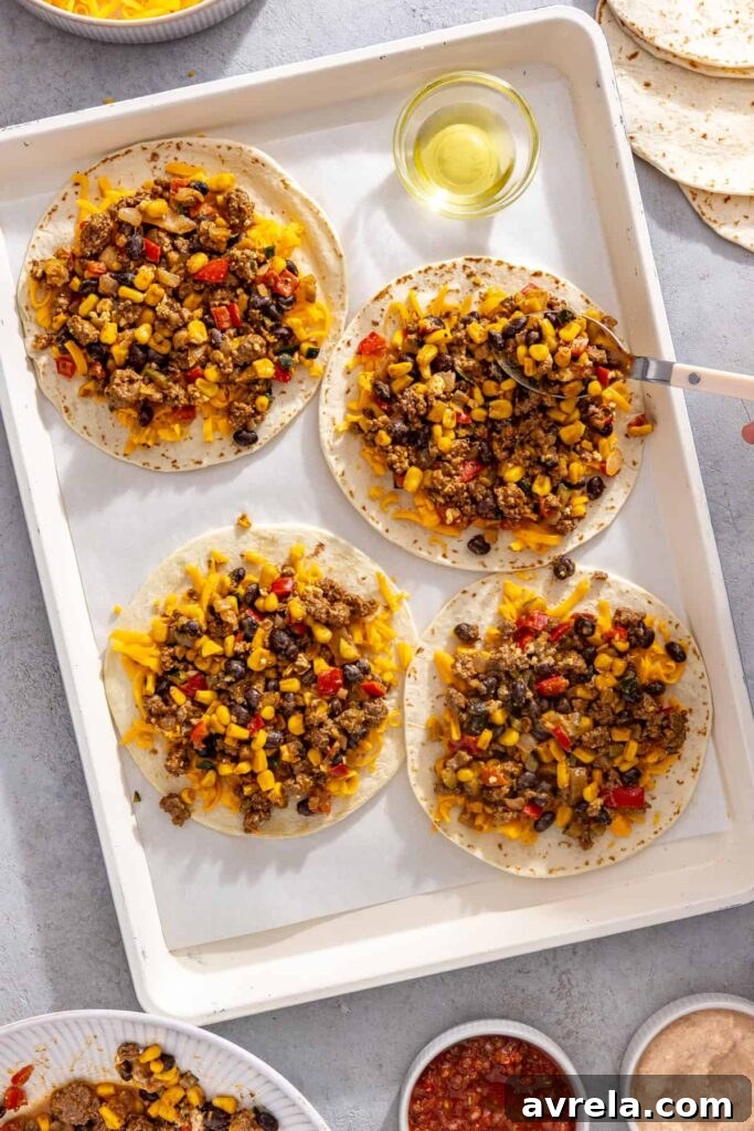 Leftover street corn taco filling spread over tortillas for sheet pan quesadillas