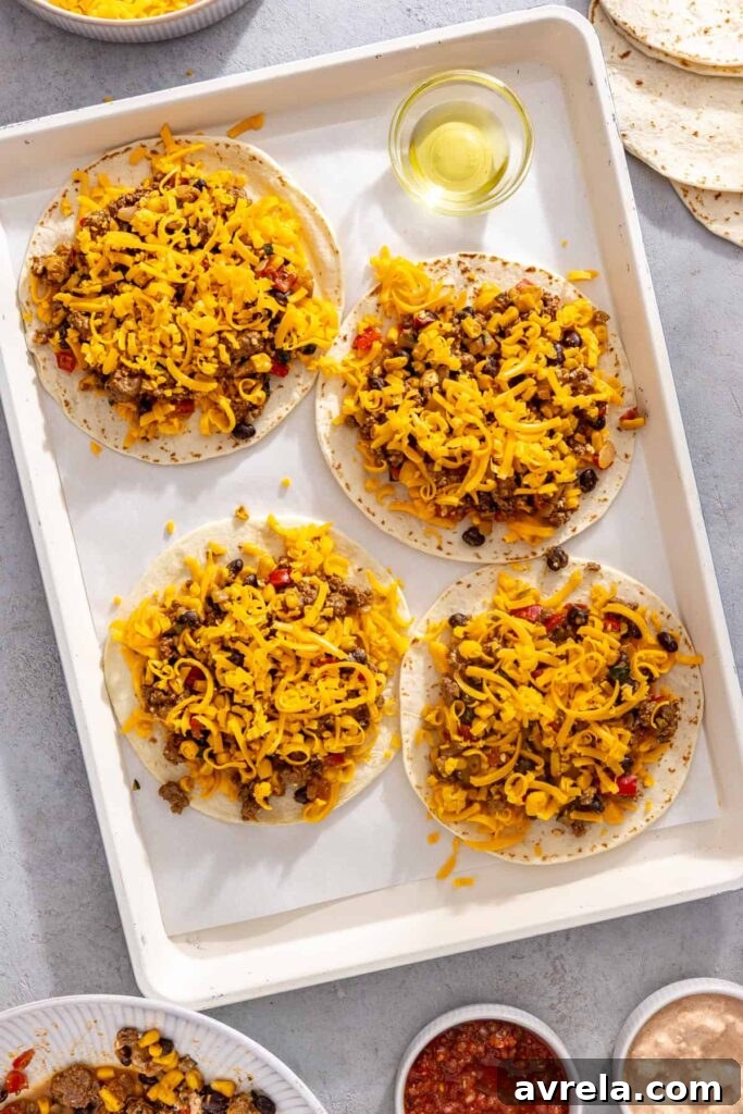 Shredded cheddar cheese sprinkled over street corn taco filling for sheet pan quesadillas
